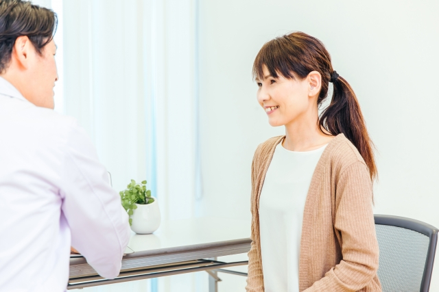 診察室で主治医と話す笑顔の女性